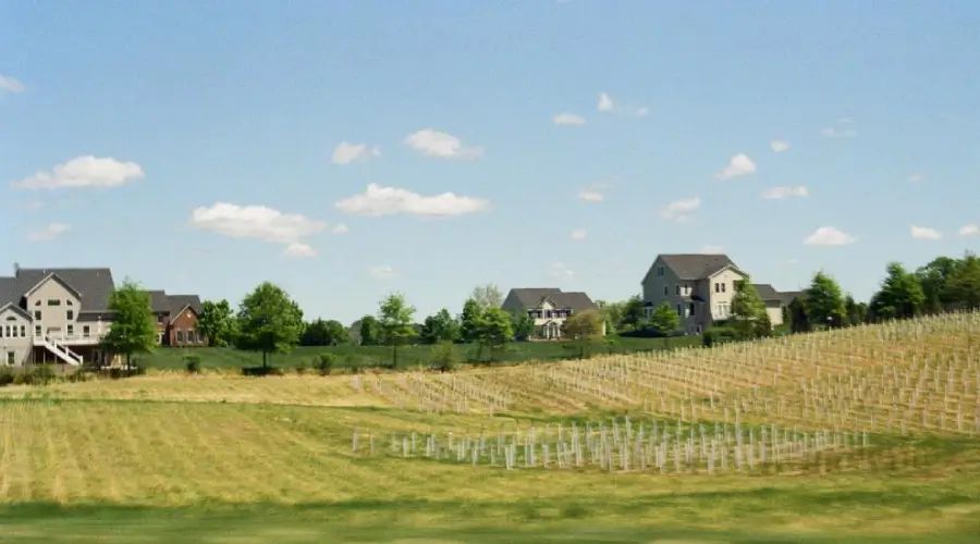 Countryside landscape in the USA with grey houses on the horizon and green hills