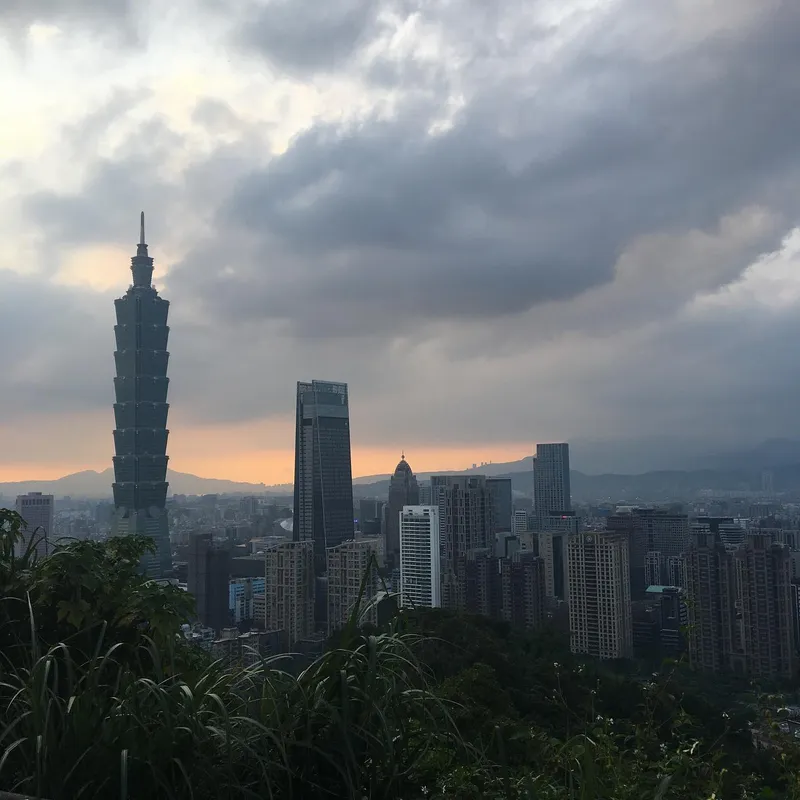 Taipei skyline at dusk with Taipei 101 silhouetted against a dramatic stormy sunset