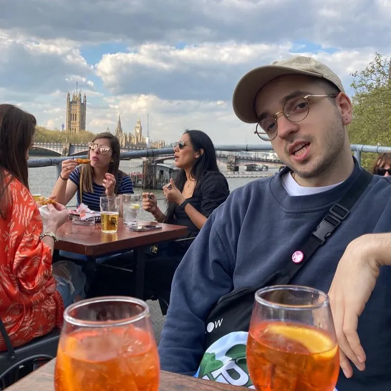 Friends at a riverside terrace with Aperol spritzes and the Houses of Parliament behind them