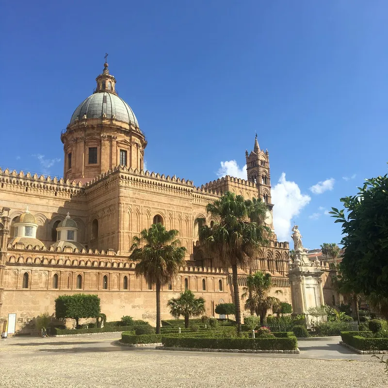 The Palermo Cathedral with its dome and bell tower framed by palm trees