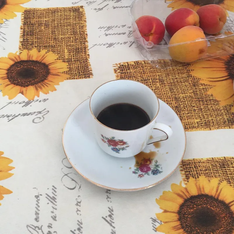 A floral porcelain espresso cup on a sunflower tablecloth