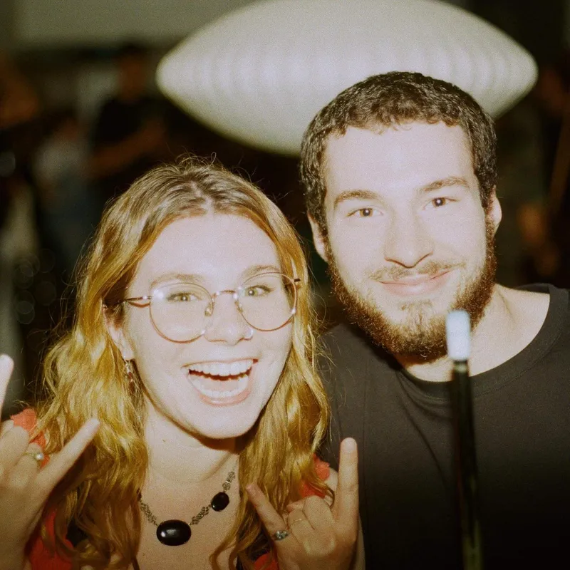 Two friends laughing and making rock signs at a party