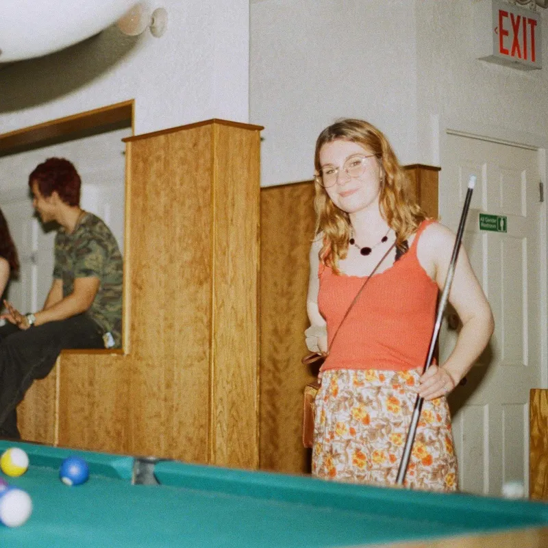 A woman holding a pool cue next to a billiard table