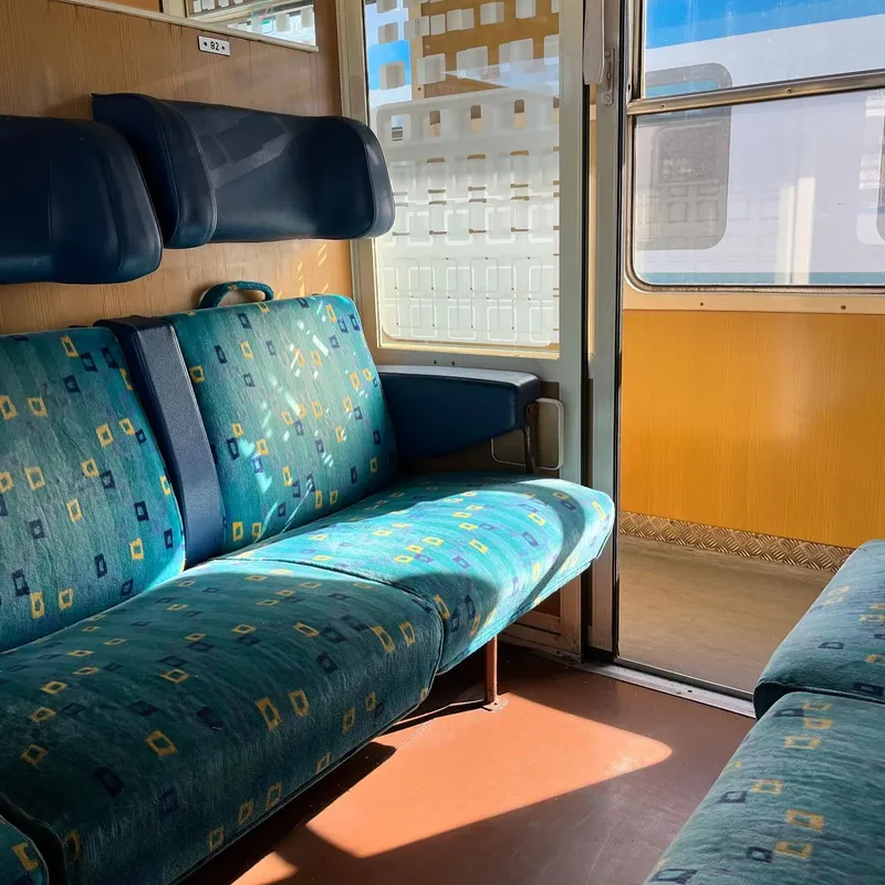 Empty seats in a sunny vintage train compartment