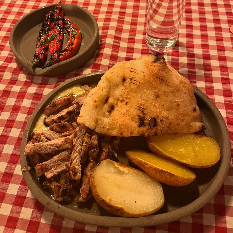 A dish of grilled meat with flatbread and potatoes