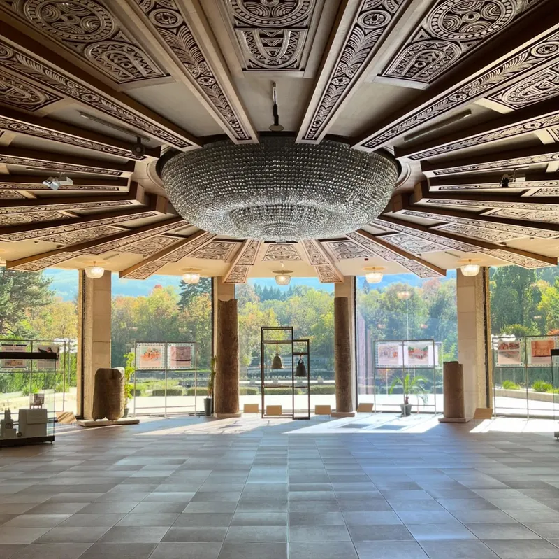An empty museum hall with an ornate carved ceiling and large chandelier