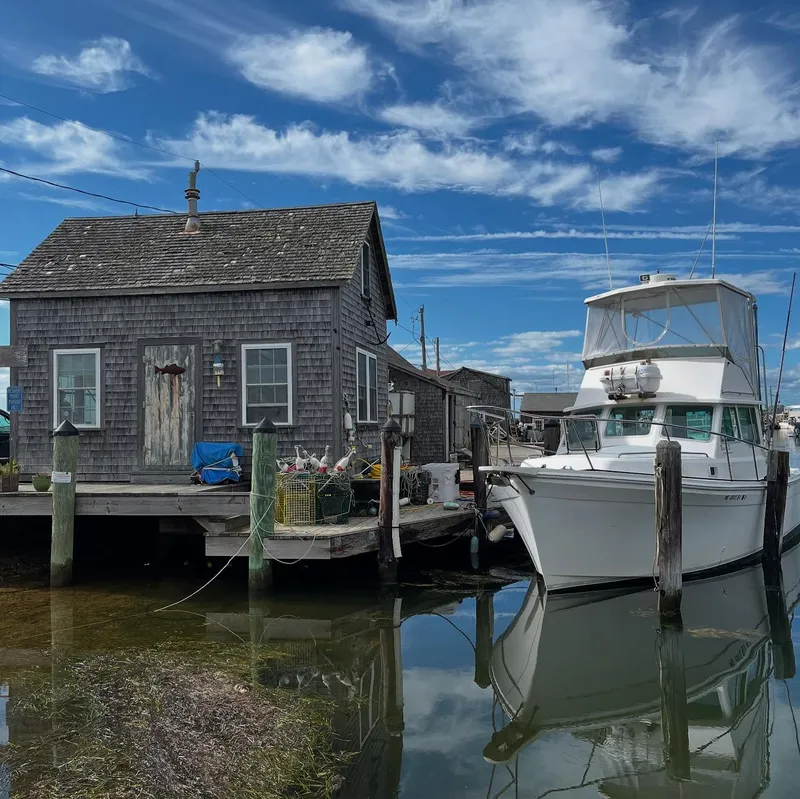 A weathered fishing shack on a dock with a white motorboat