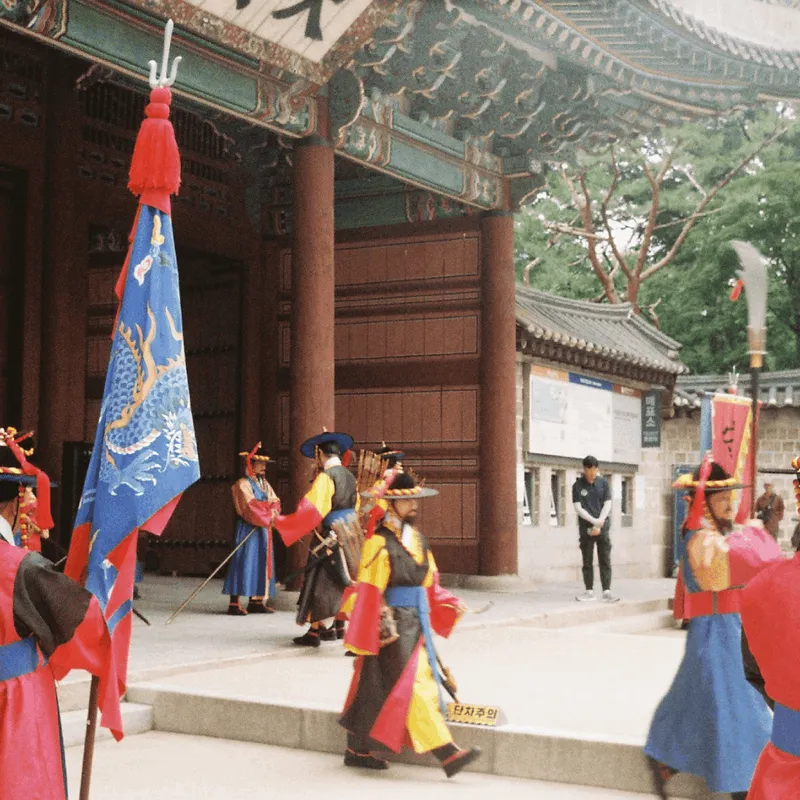 Group of men in traditional Korean military uniforms during the changing of the guard at Deoksung Temple in Seoul